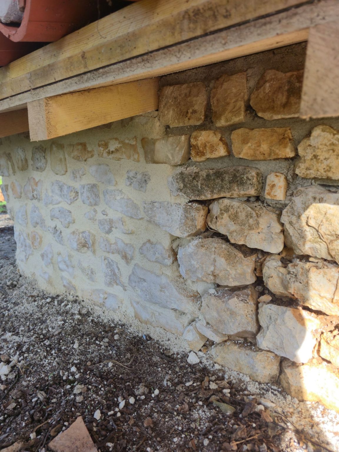 Rejointoiement à la chaux d'un mur en pierre à Terres-de-Haute-Charente, partie refaite et partie d'origine