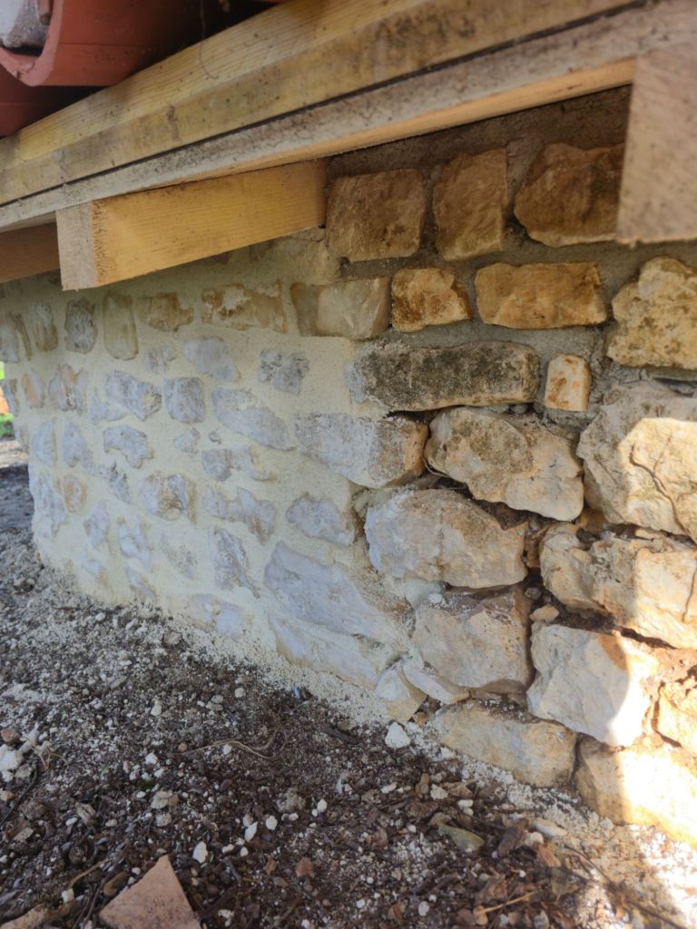 Rejointoiement à la chaux d'un mur en pierre à Terres-de-Haute-Charente, partie refaite et partie d'origine